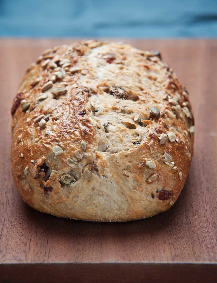 A loaf of country bread with seeds on a wooden board