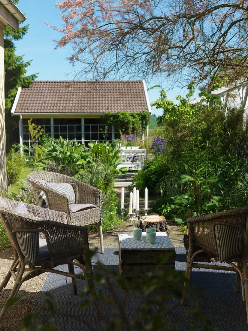 Idyllic seating area on terrace with wicker furniture and view of summer garden