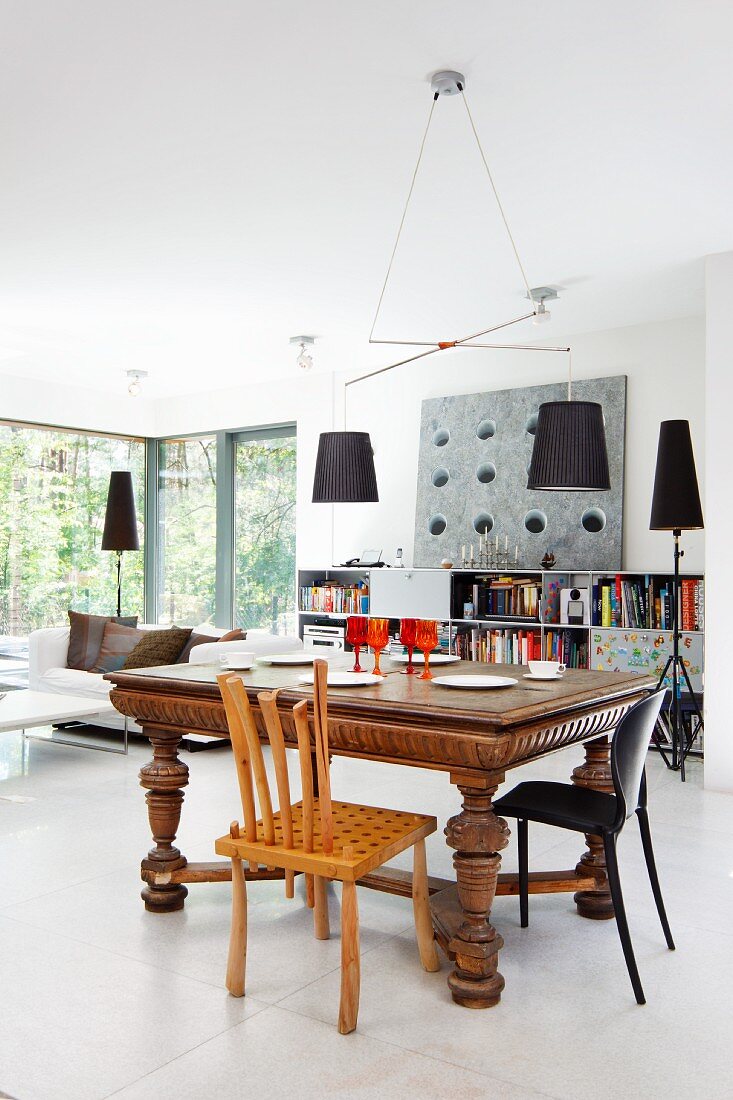 Lamps with black lampshades in open-plan interior with central dining area in eclectic mixture of styles