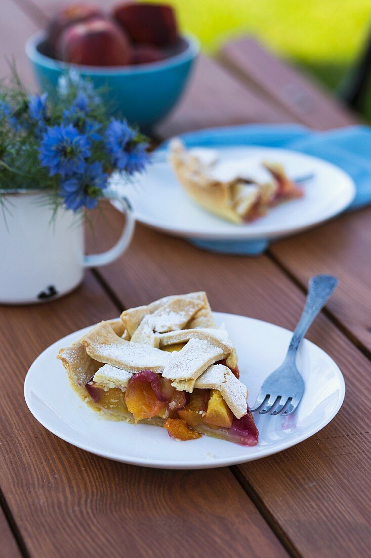 Two slices of peach pie on a wooden table in a garden