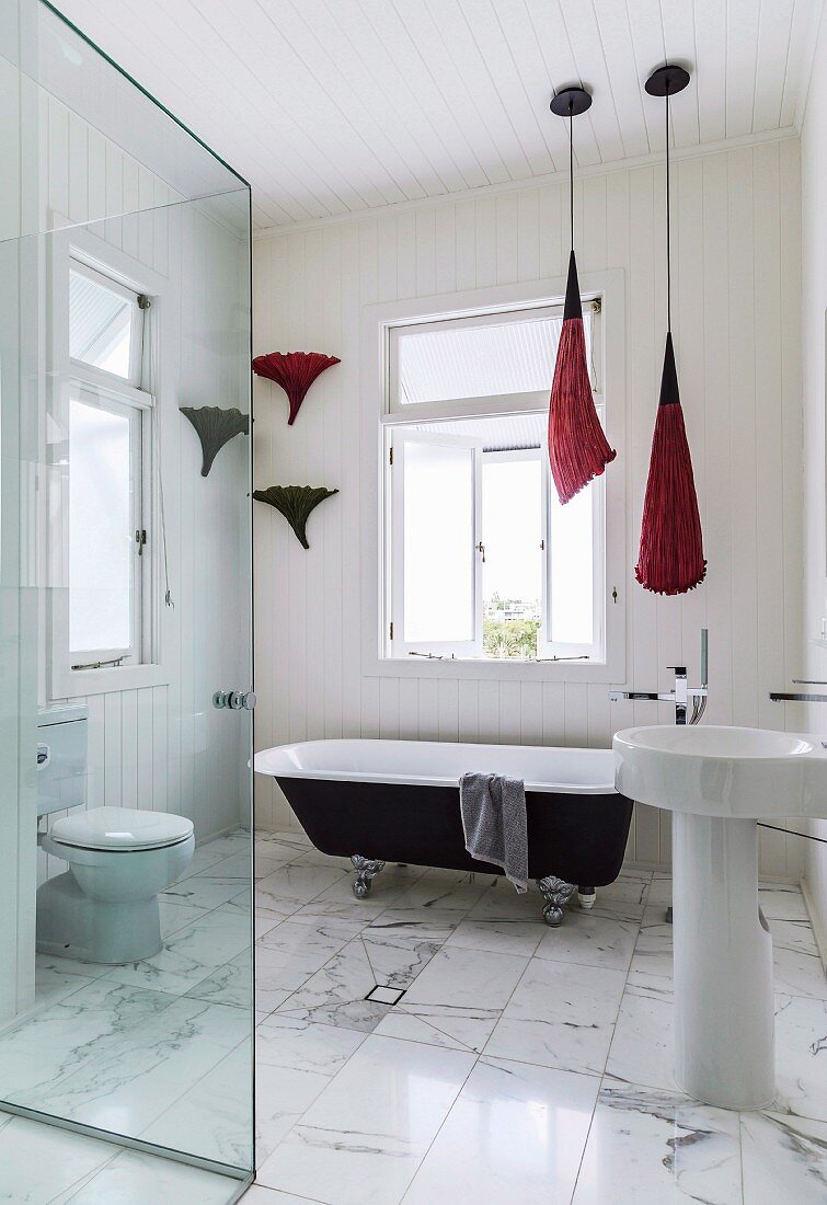 Blick in modernes, elegantes Bad mit Marmorboden, im Hintergrund freistehende Vintage Badewanne vor Fenster
