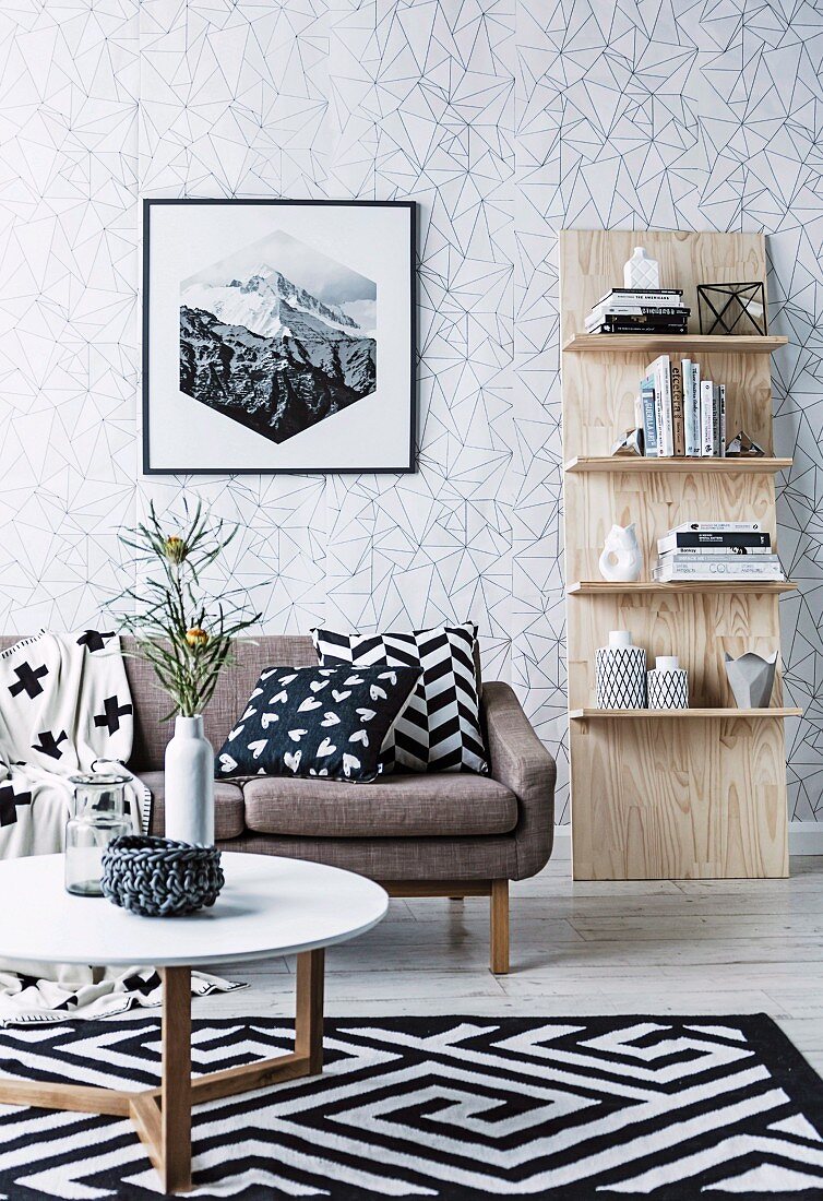 Shelf leaning against the wall, sofa with pillows, carpet with black and white pattern