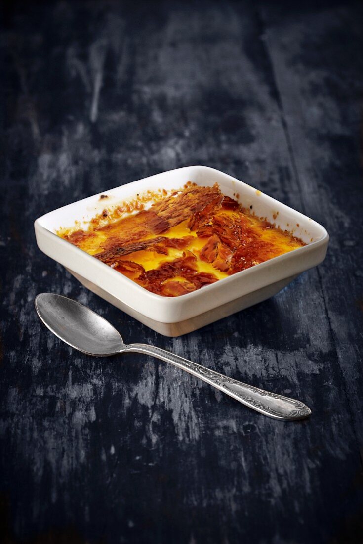Crème brûlée in a square dish with a spoon