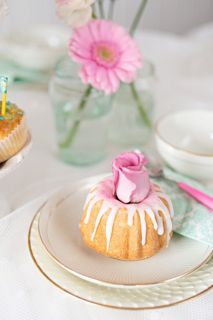 A mini iced Bundt cake decorated with roses