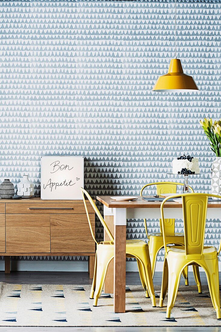 DIY cube lamp decorated with handwriting on sideboard behind dining table with yellow retro chairs