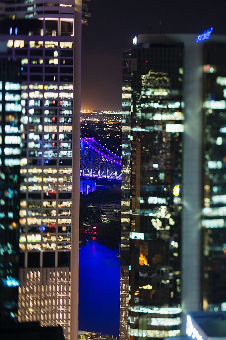 Durch die Skyline sieht man die erleuchtete Story Bridge, Brisbane