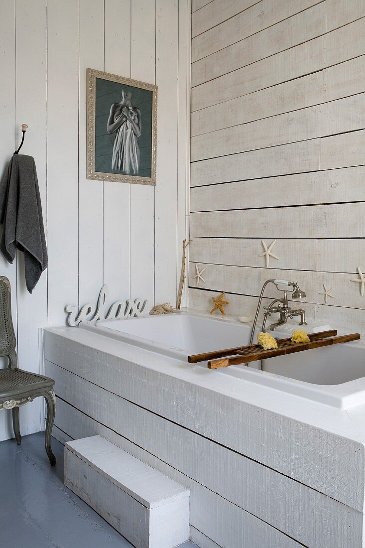 Eingebaute Badewanne mit weisser Holzverkleidung an Frontseite und an Wänden