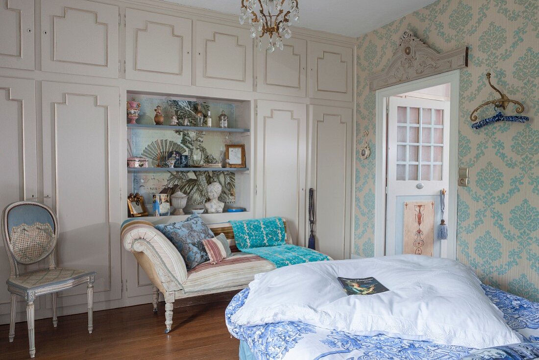 Elegant fitted wardrobes with open-fronted shelving modules and chaise longue in antique-style bedroom