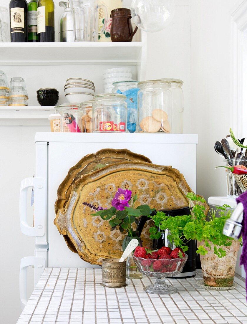 Detail of kitchen counter with tiled worksurface in front of storage jars on top of fridge