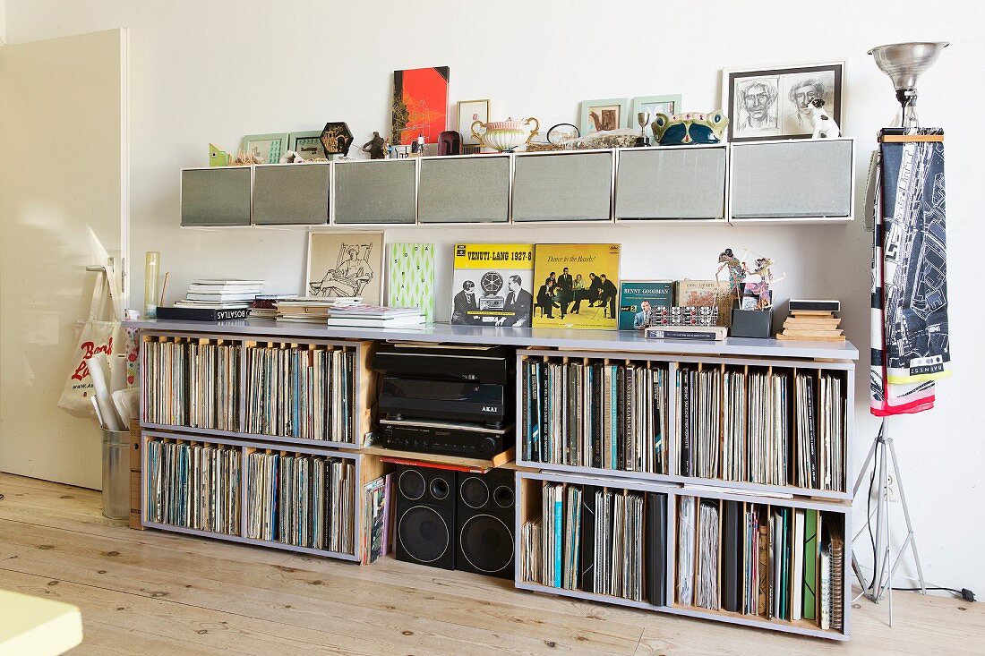 Record collection and hi-fi in open-fronted sideboard below row of wall-mounted cabinets