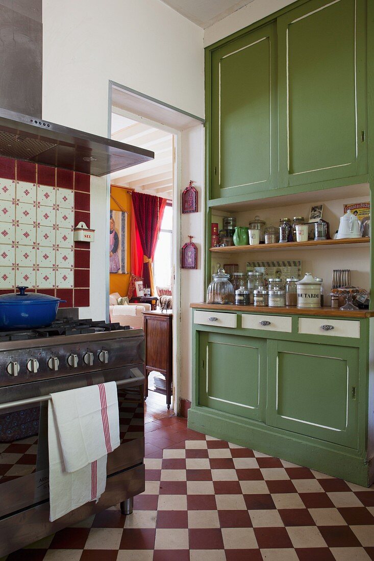 Traditionelle Küche mit rot-weißem Schachbrettboden, grünem Küchenbuffet und Gasherd