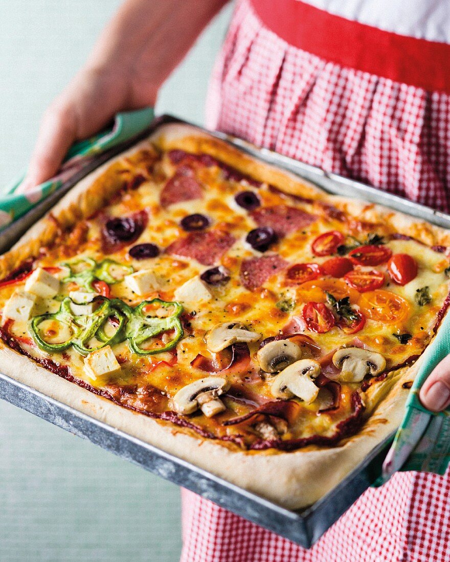 Frau hält Backblech mit gebackener Deep Pan Pizza