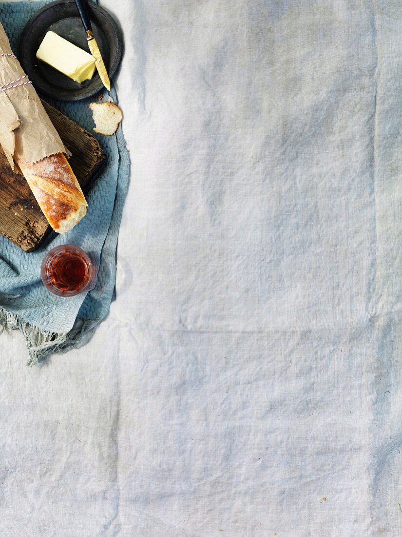 Bread, baguette and red wine on white picnic blanket