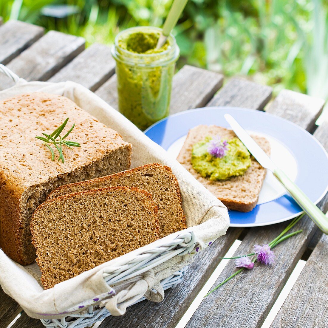 Homemade bread in a bread basket with a jar of herb spread next to it