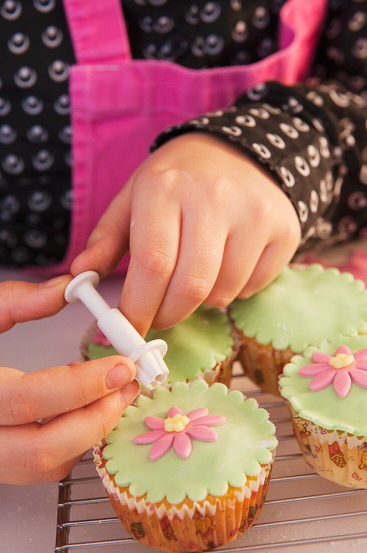 A little girl decorating a cupcake with sugar flowers