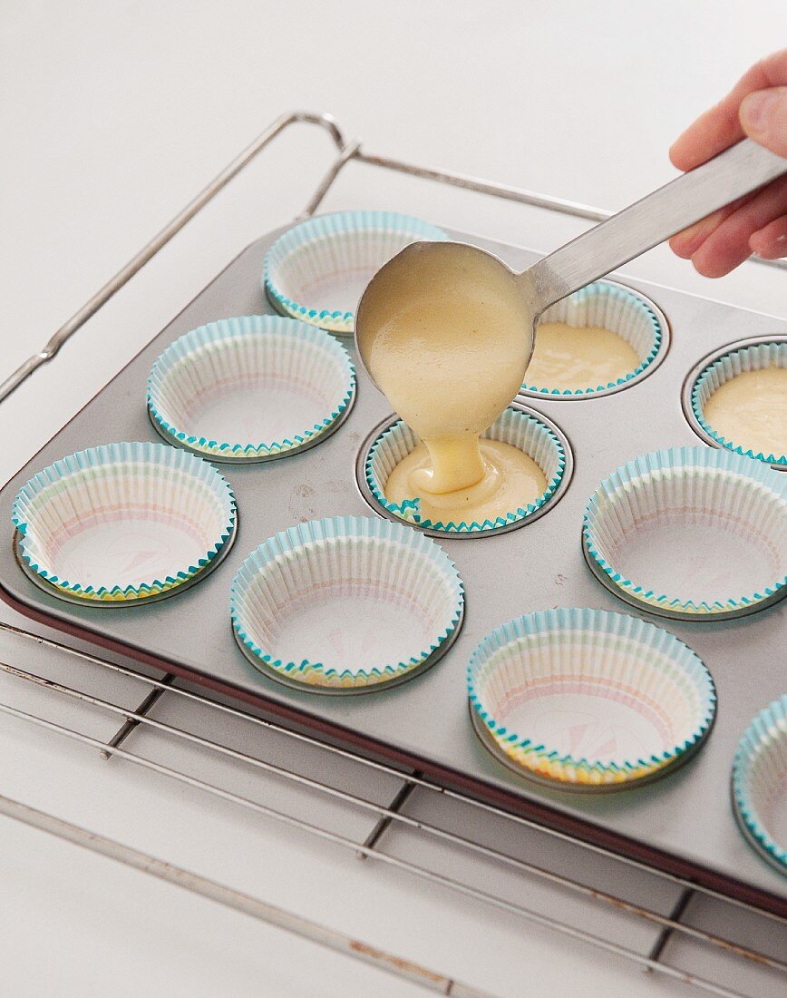 Cupcake mixture being poured into baking cases