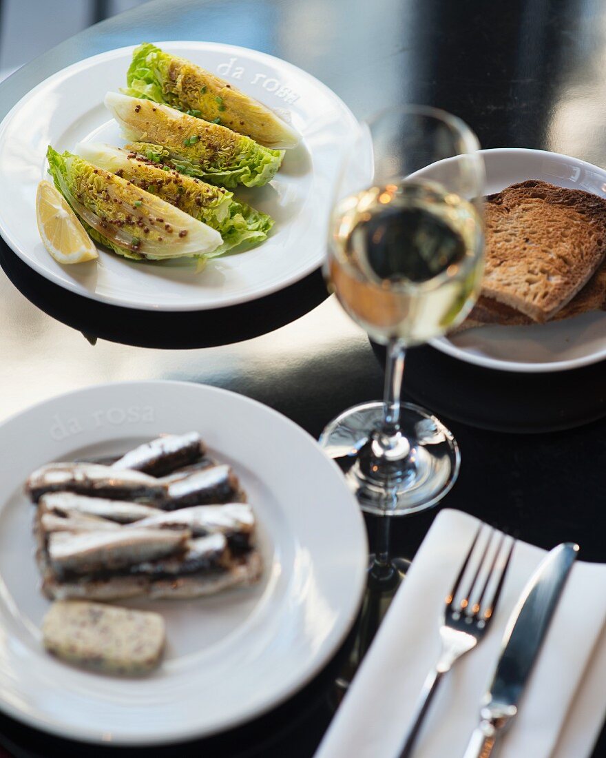 Verschiedene Tapas (Sardinen, Salat) mit Wein und Brot