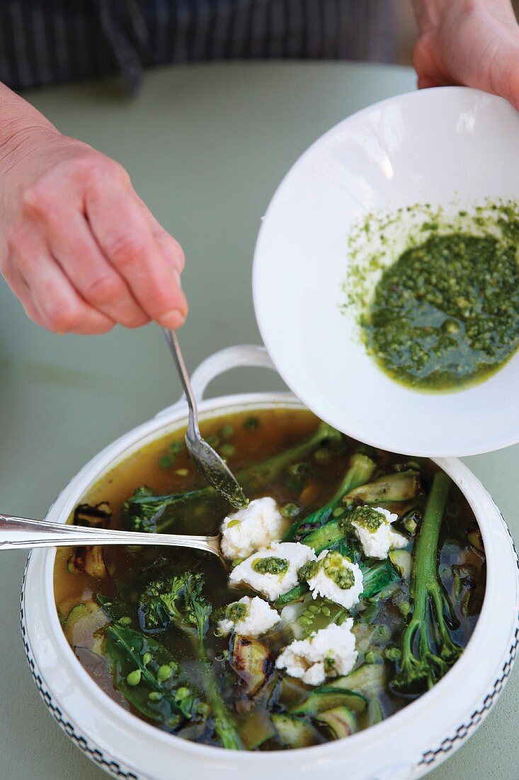 Soup being garnished with pesto