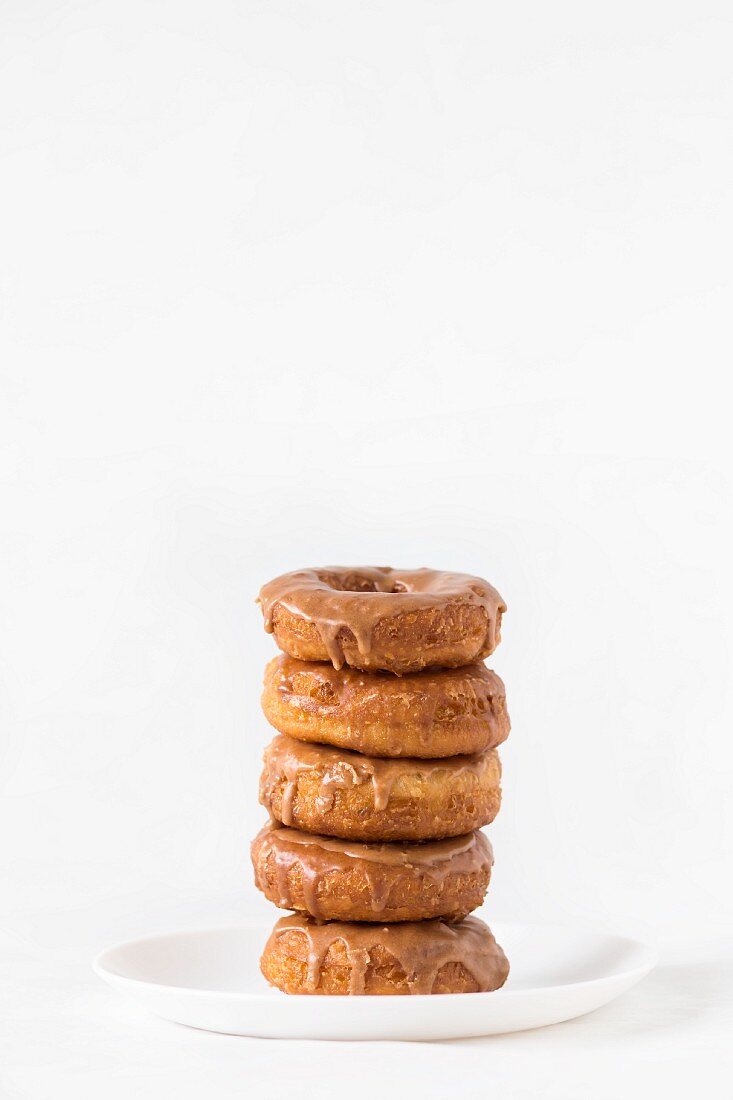 A stack of cinnamon-glazed doughnuts on a white plate