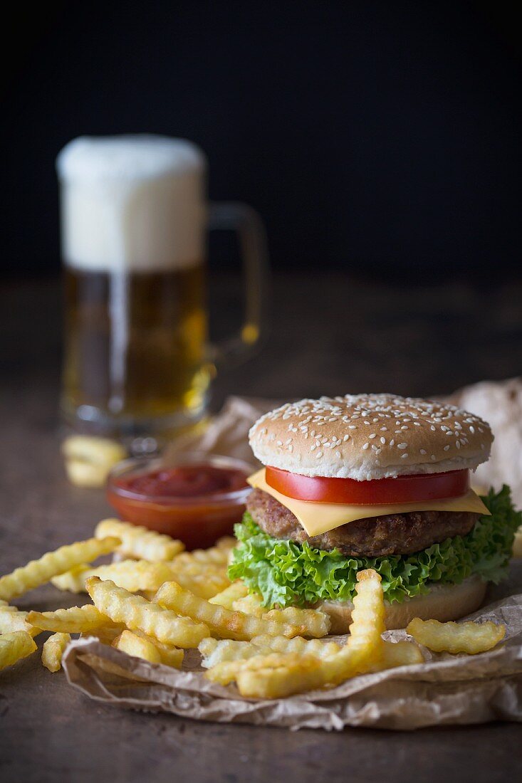 A homemade cheeseburger with chips, tomato sauce and a glass of beer