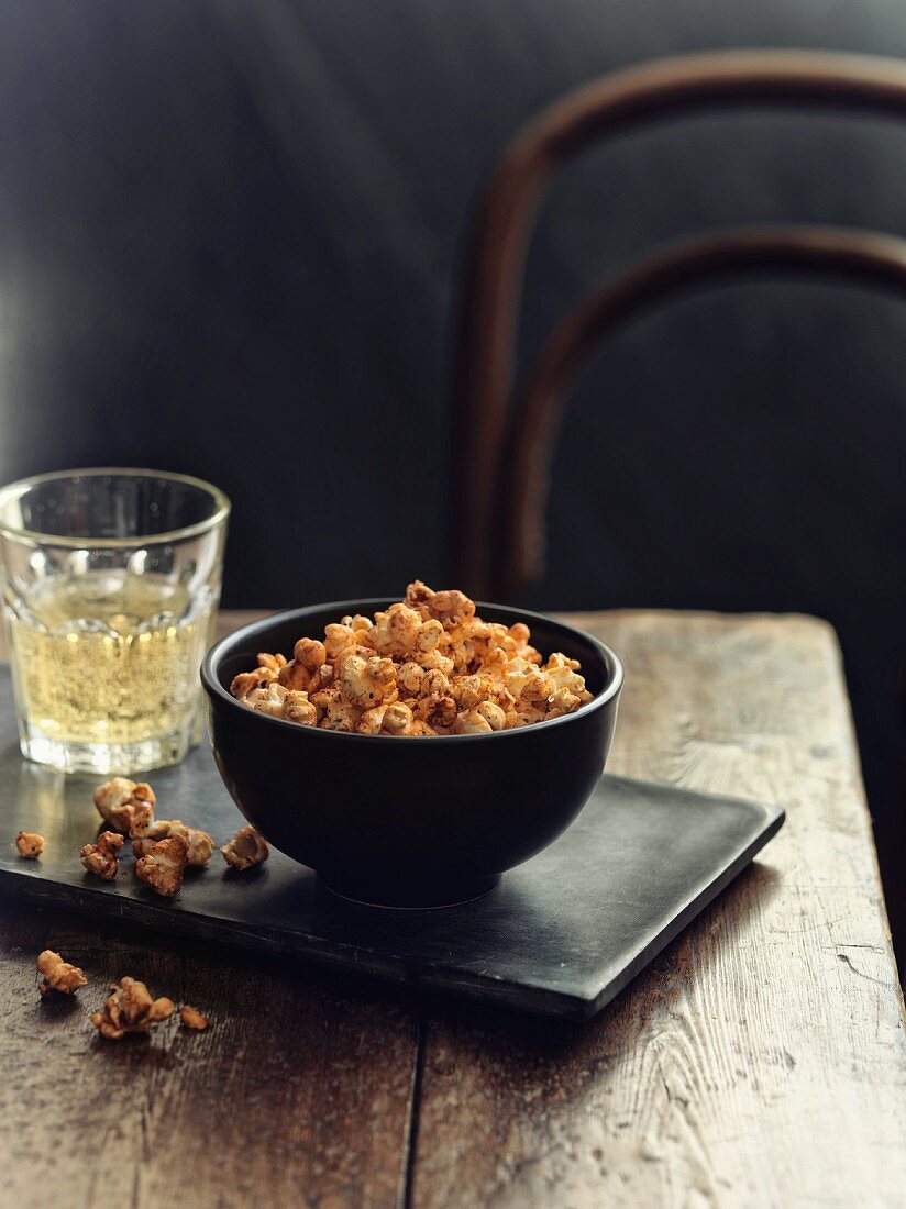 A bowl of spiced popcorn next to a glass of white wine