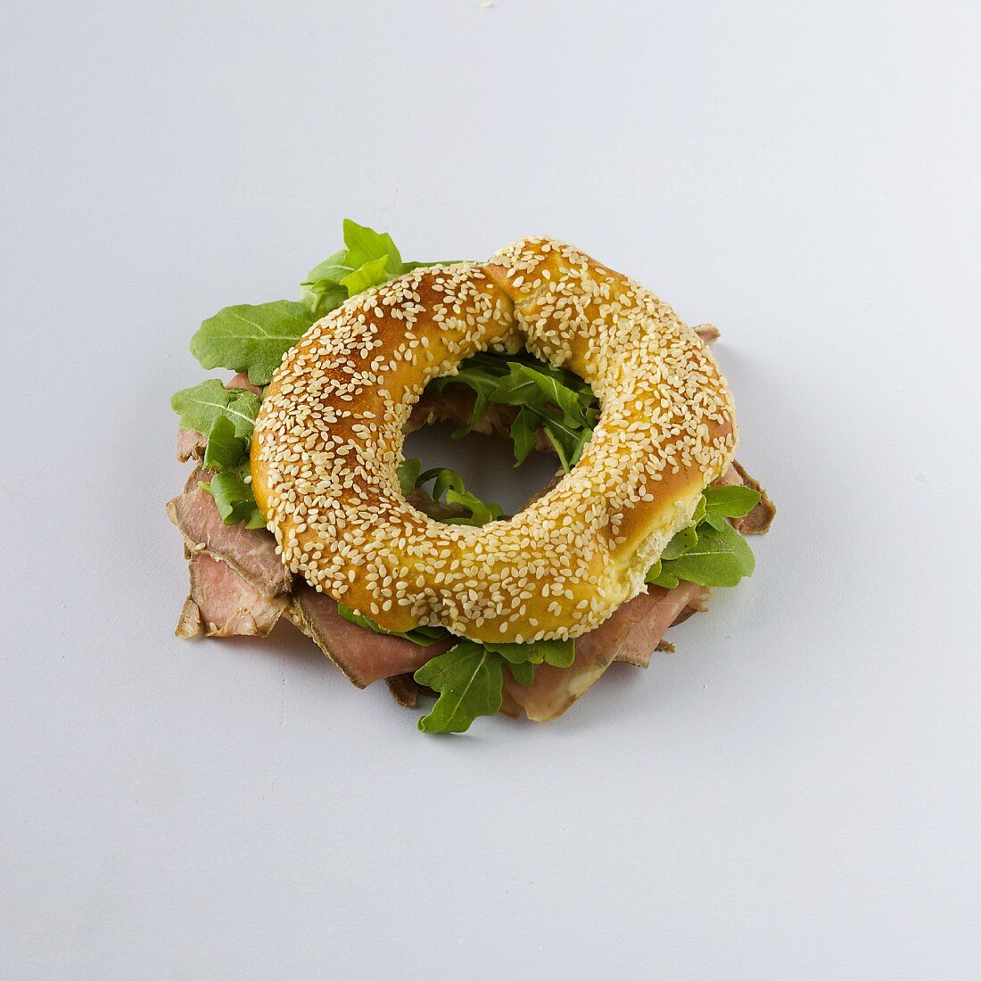 A sesame seed bagel with roast beef and rocket