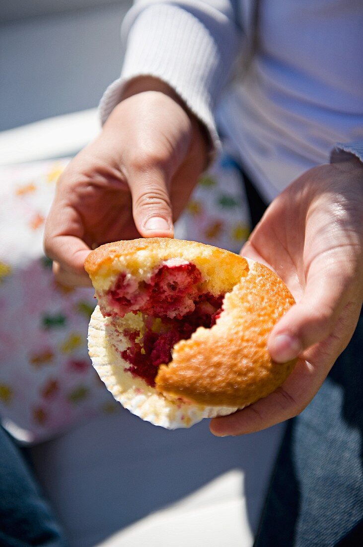 Einen Himbeermuffin auseinanderbrechen