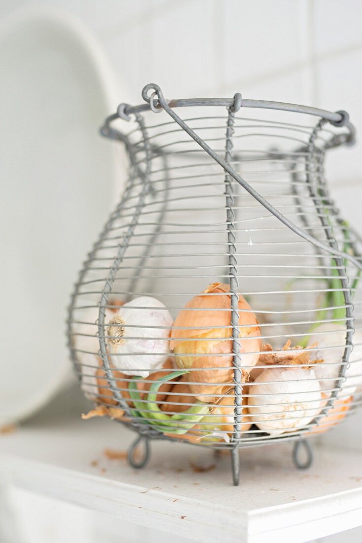 Wire basket of onions and garlic bulbs