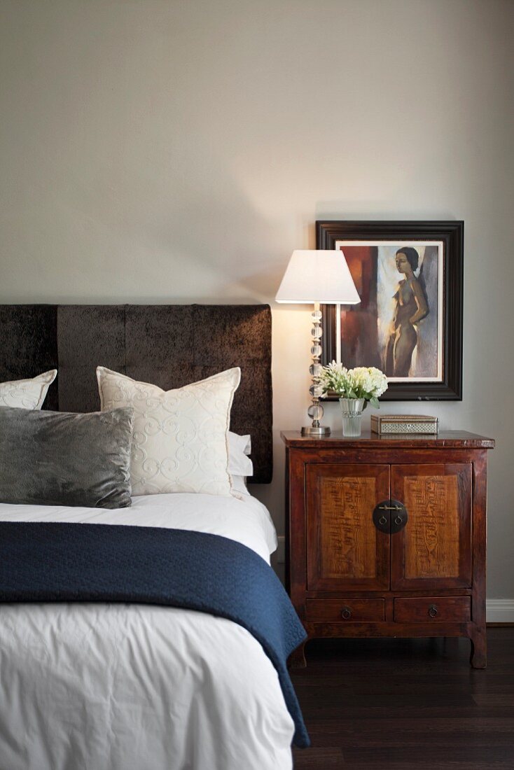 Bed with velvet headboard an antique Oriental bedside cabinet