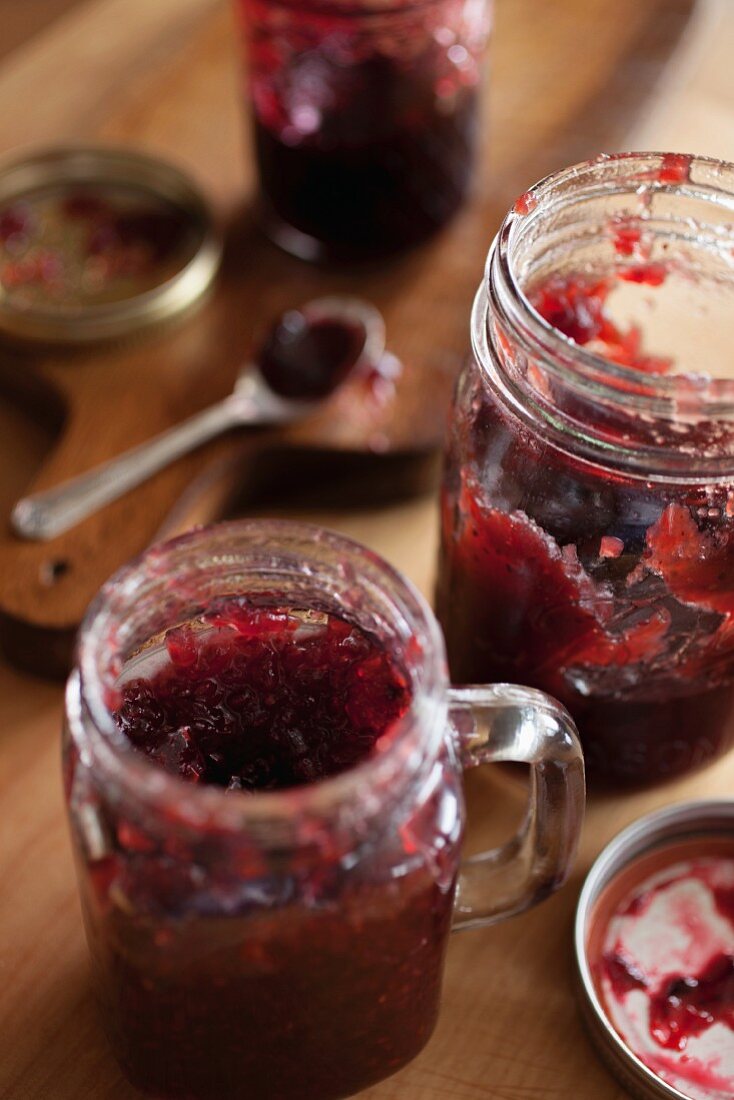 Jars of blueberry and strawberry jam on a wooden table