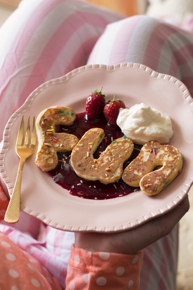 Letter-shaped pancake on berry purée with cream