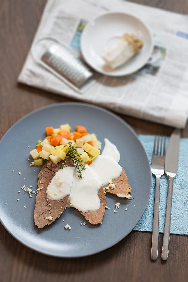 Prime boiled beef with a horseradish sauce and bouillon potatoes accompanied by fresh horseradish and the daily newspaper