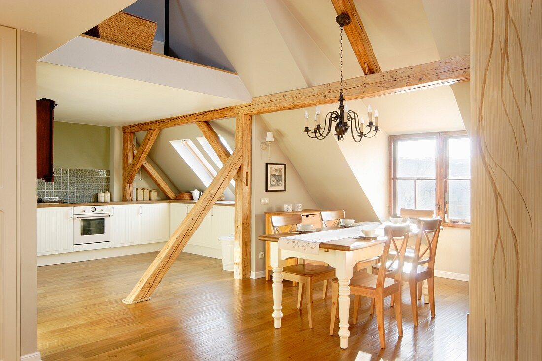 Open-plan kitchen and dining area in converted attic with rustic wooden roof beams
