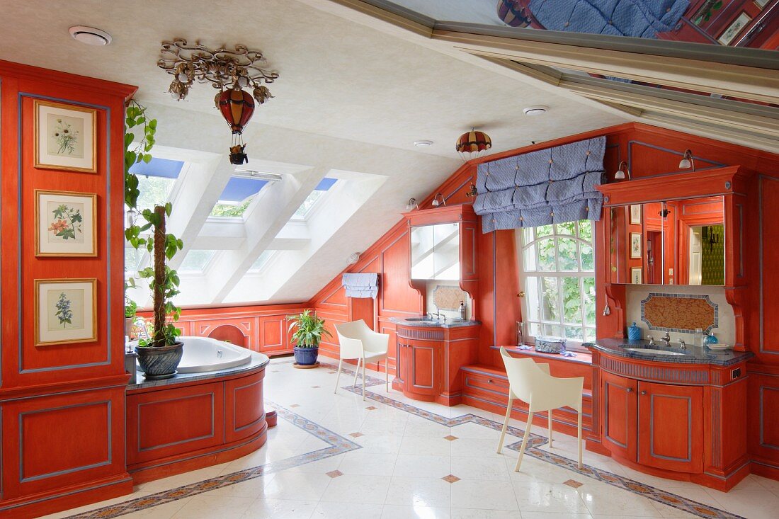 Luxurious bathroom with custom fitted cabinets painted red and armchairs in attic interior