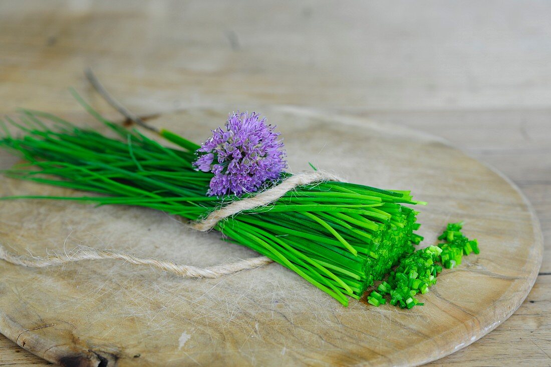 Fresh chives with flowers on a wooden board