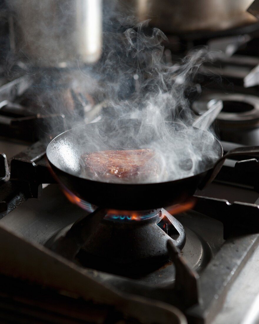 Meat in a pan on a gas stove