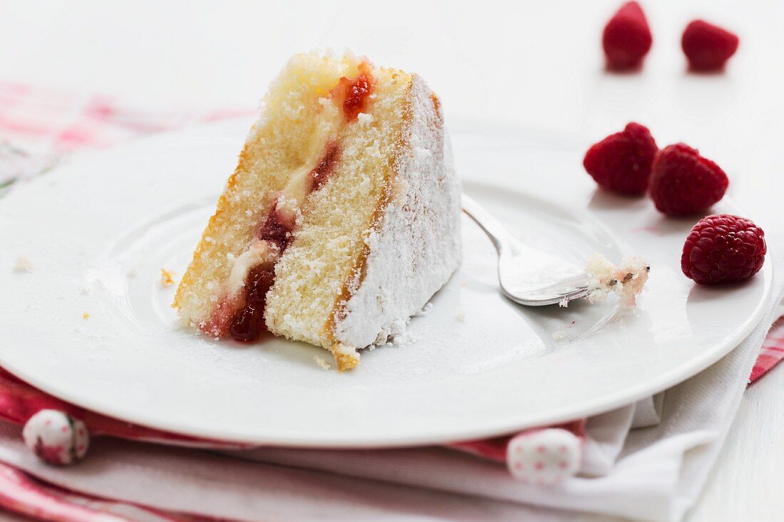 A slice of Victoria sandwich cake with raspberries