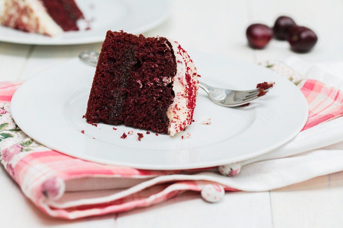 A slice of Red Velvet cake on a plate with a fork