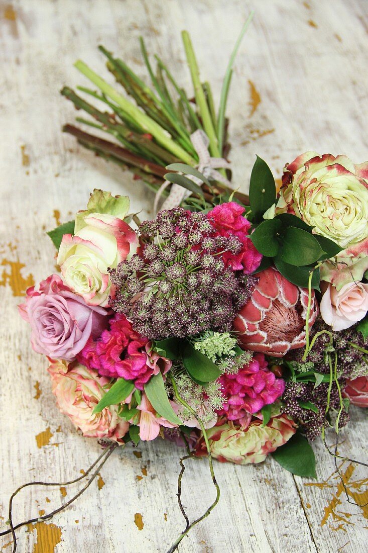 Blumenstrauss aus Rosen und Protea auf Vintage Holzablage