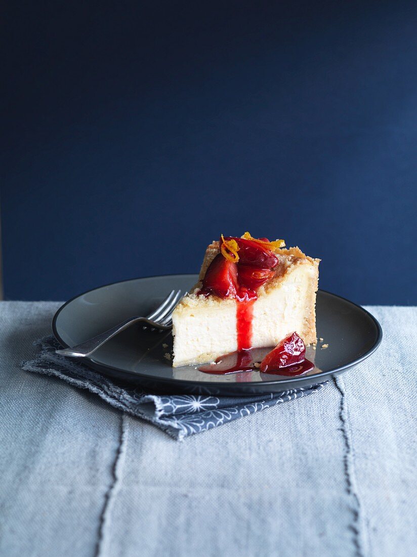 Ein Stück Käsekuchen mit Pflaumen, Orangen und Streuseln