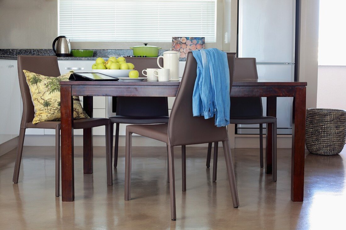 Dark wooden dining table and grey plastic chairs on polished concrete floor