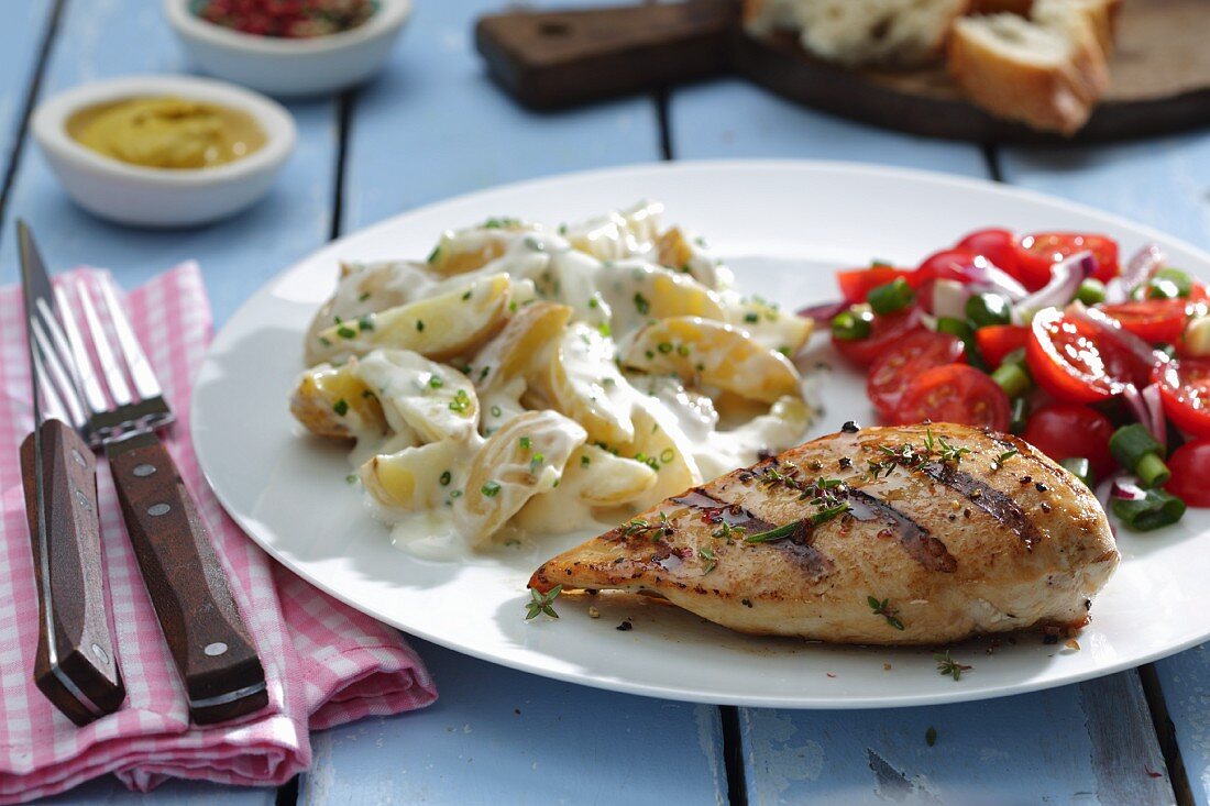 Grilled chicken breast with potato salad and tomato salad