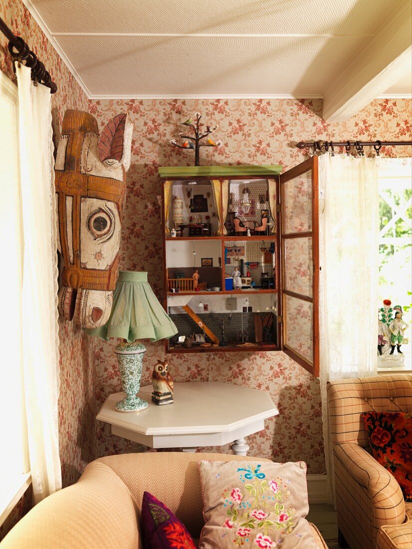 Sofa, white-painted octagonal table and painted wooden horse head in corner of living room