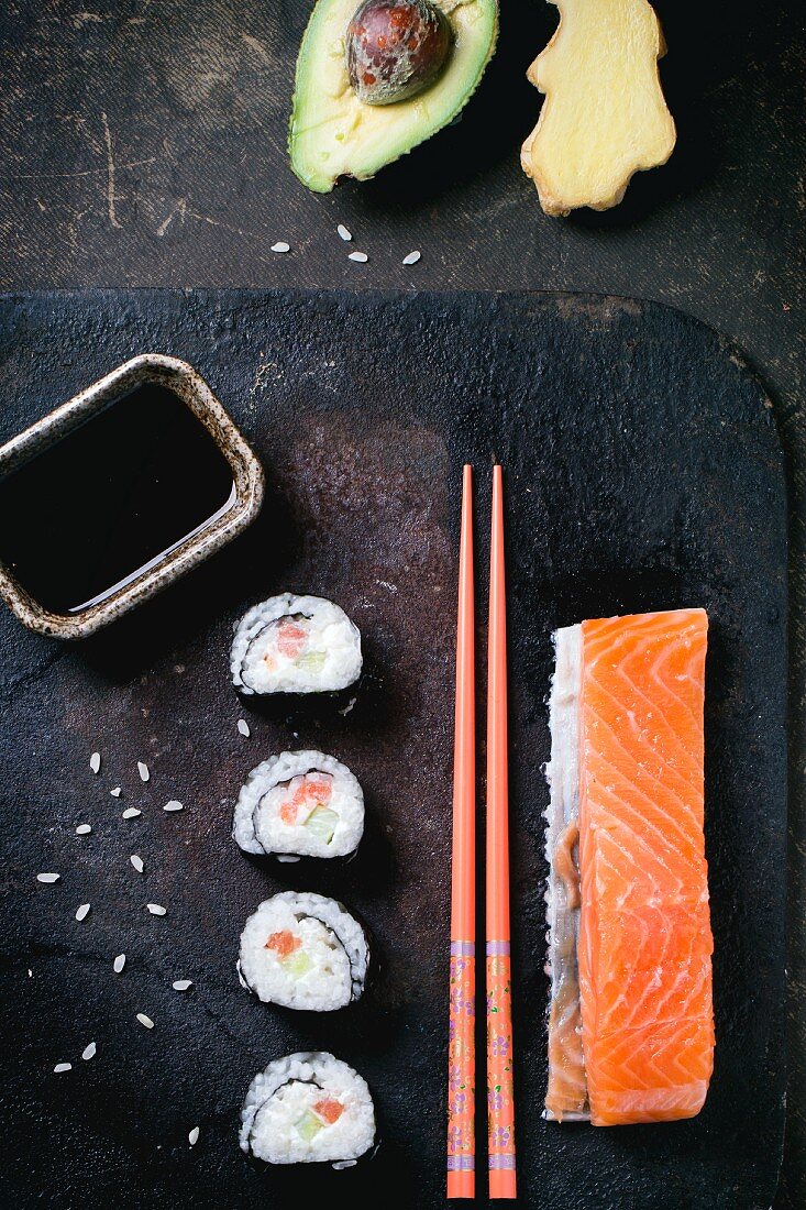 Maki sushi with salmon, avocado, ginger, soy sauce and chopsticks