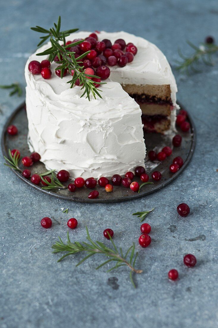 A winter cranberry cake with vanilla frosting and rosemary