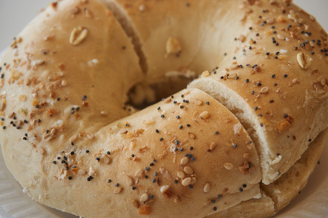 A sesame and poppy seed bagel with butter, sliced
