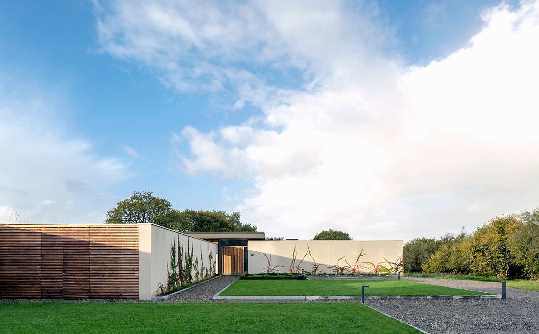 One-storey, free-standing house with edged lawns and gravel paths in sunshine