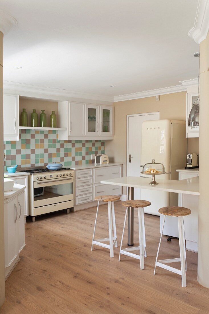 White fitted kitchen with mosaic splashback, retro cooker, retro fridge, breakfast bar & bar stools