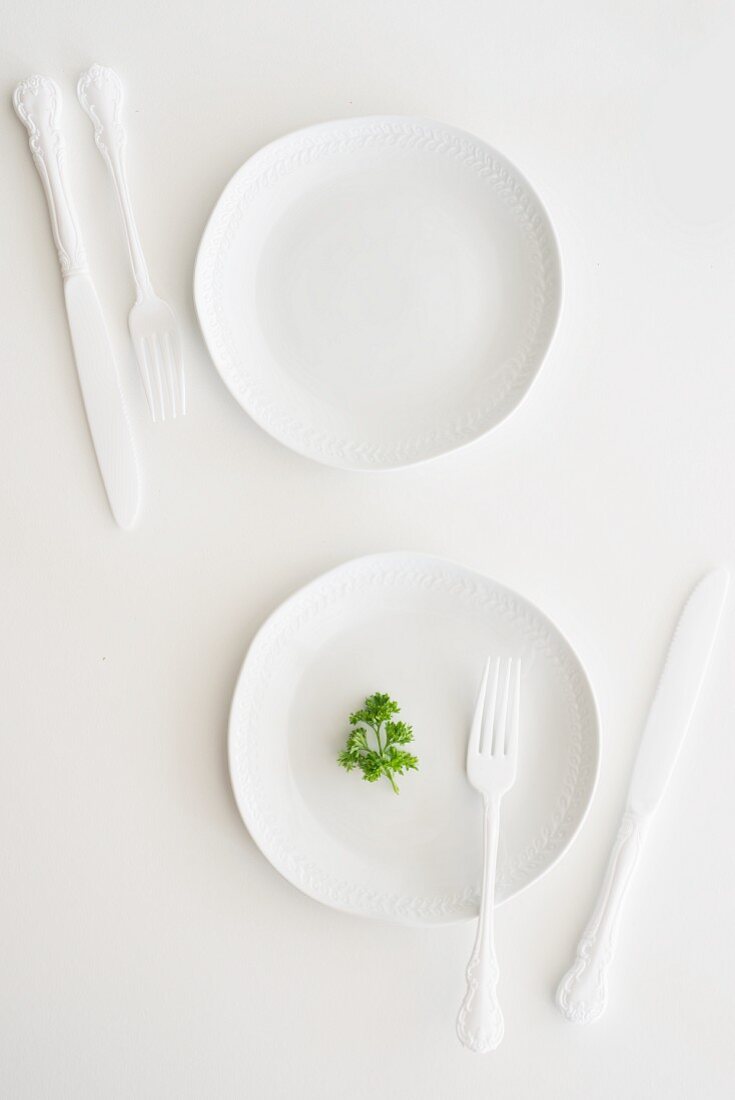 White plates, cutlery and parsley