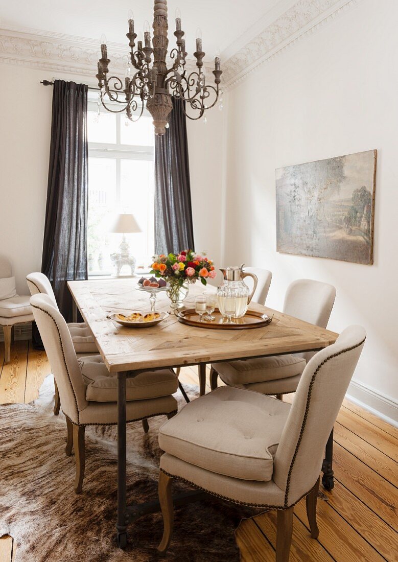 Beige gepolsterte Stühle an rustikalem Esstisch mit Kronleuchter in Wohnzimmerecke mit traditionellem Flair
